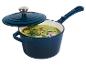 Blauwe steelpan met deksel, gevuld met groene soep gegarneerd met kruiden en roze peperkorrels