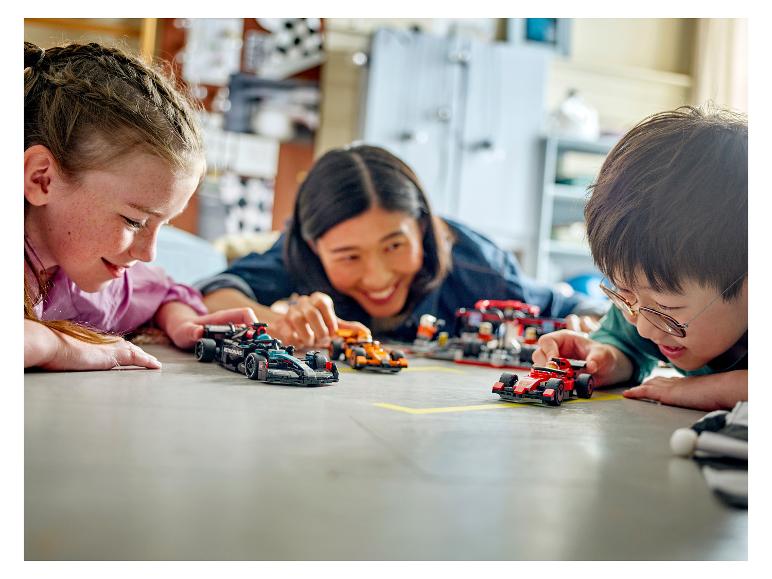 Drie kinderen spelen met LEGO Speed Champions raceauto's op de vloer.