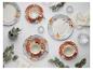Bloemige serviessets met borden, kopjes en schotels, geaccentueerd met eucalyptus en kaarsen.