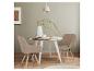 Eetkamer met een ronde tafel, twee beige stoelen en een vaas met takken.
