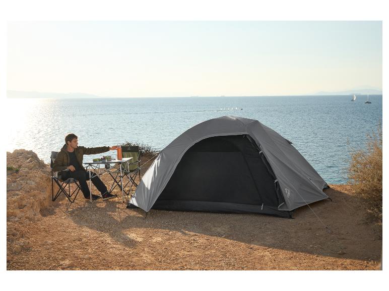 Man kampeert aan zee met een CRIVIT tent, klapstoelen en een tafel.