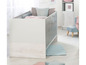 Een babybed met houten details en een zacht blauwe mat.
