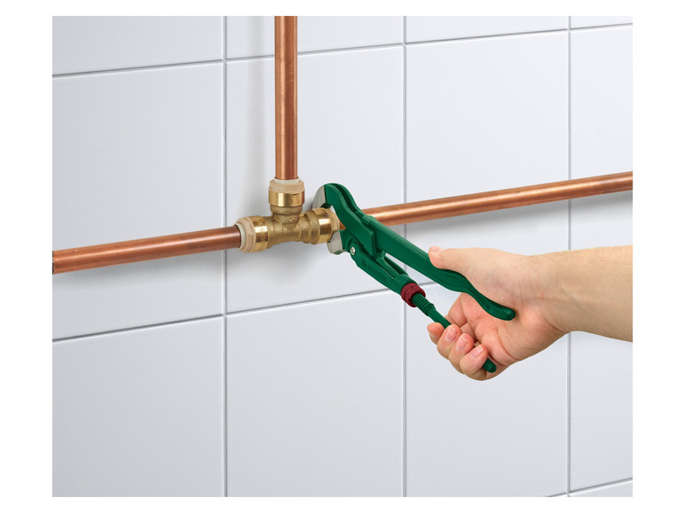 Een groene waterpomptang wordt gebruikt om koperen leidingen te bevestigen.