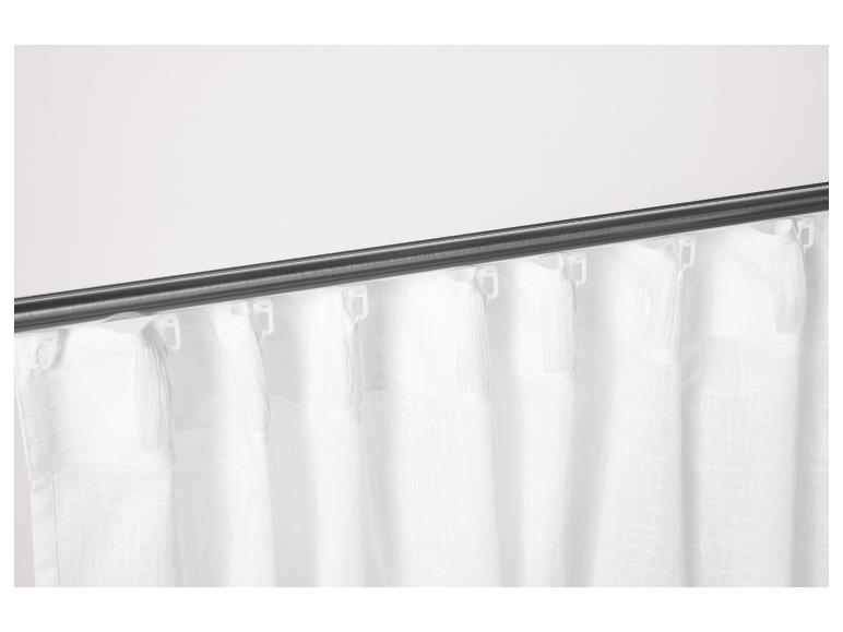 Witte gordijnen met franjes, opgehangen aan een donkere stang.