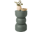 Groene driedelige decoratieve vaas met eucalyptus takken en een kom met kiezels.