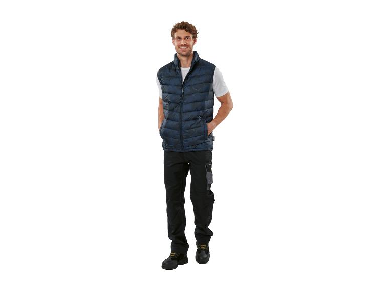 Man draagt een donkerblauw gewatteerd vest, een wit T-shirt en een zwarte werkbroek.