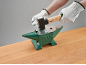 Een persoon met handschoenen die een hamer en aambeeld gebruikt om een metalen plaat te buigen.