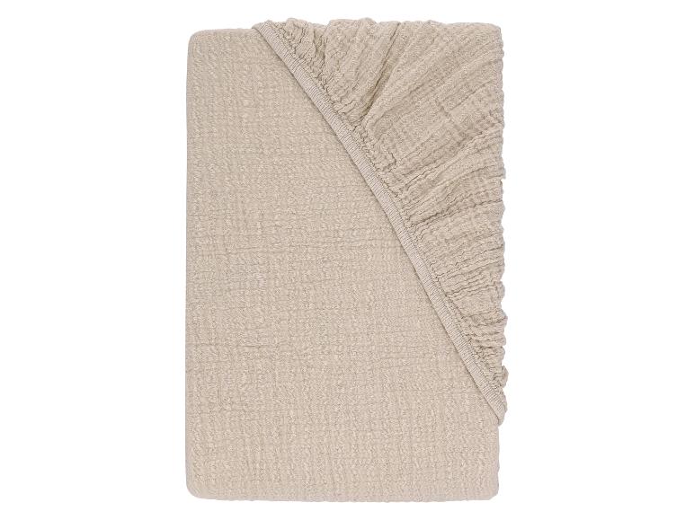 Gevouwen lichtbeige mousseline hoeslaken.