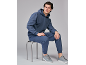 Man in blauwe hoodie en bijpassende broek, zittend op een kruk.