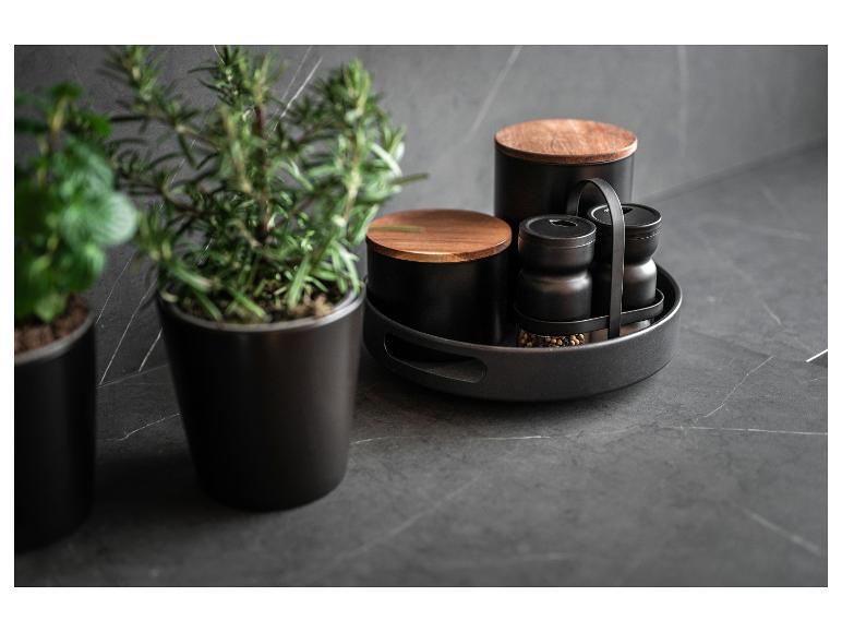 Zwarte kruidenset met houten details op een donker aanrecht.