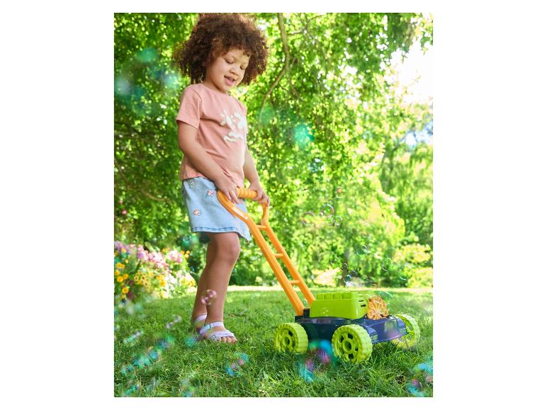 Kind speelt met een zeepbel-grasmaaier in de tuin.