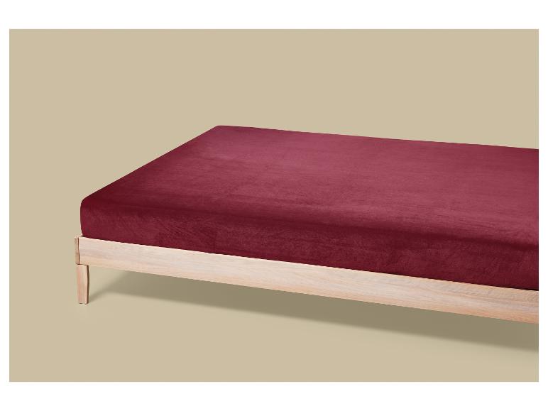 Bordeauxrood fluwelen hoeslaken op een licht houten bedframe.