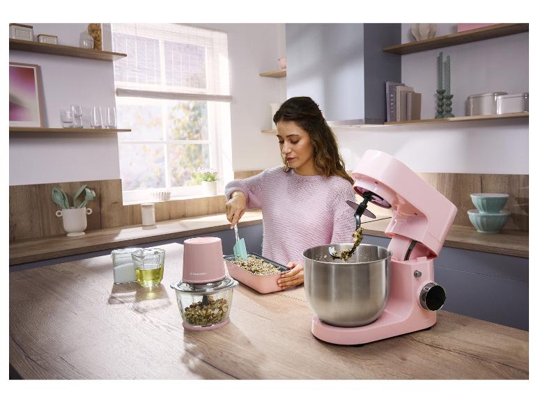 Vrouw kookt in keuken met roze keukenmachine en hakmolen.