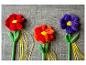 Drie pluche bloemen in het rood en paars met gele linten.
