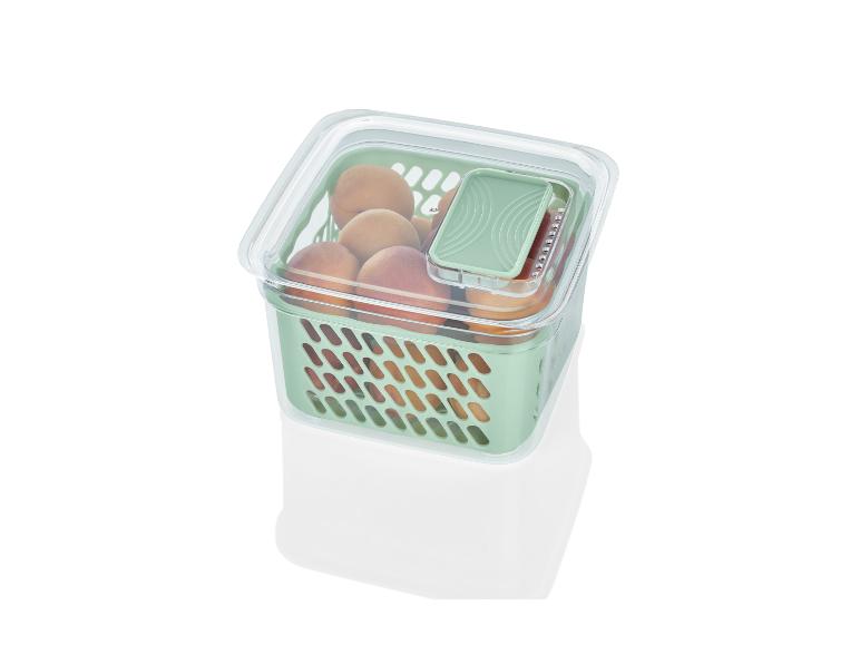 Een groene plastic opbergdoos met deksel, gevuld met abrikozen.