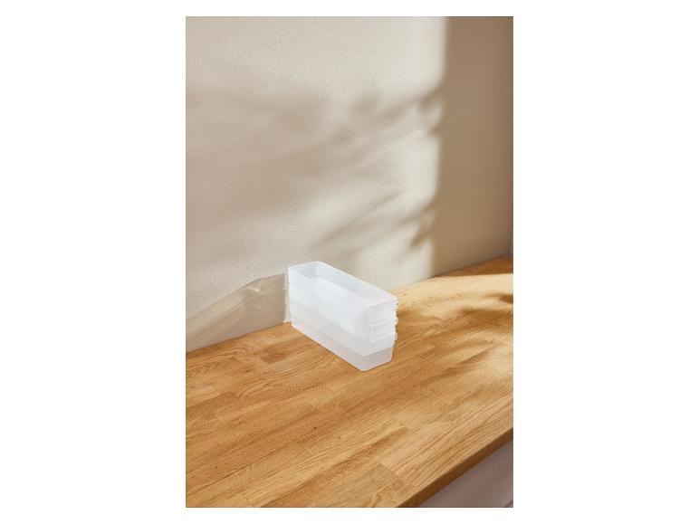 Transparante plastic organizers gestapeld op een houten oppervlak met schaduwen.