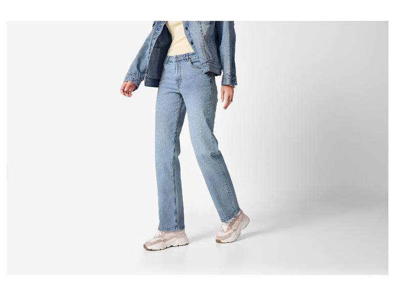 Persoon draagt een lichtblauwe spijkerjas, jeans en beige sneakers.