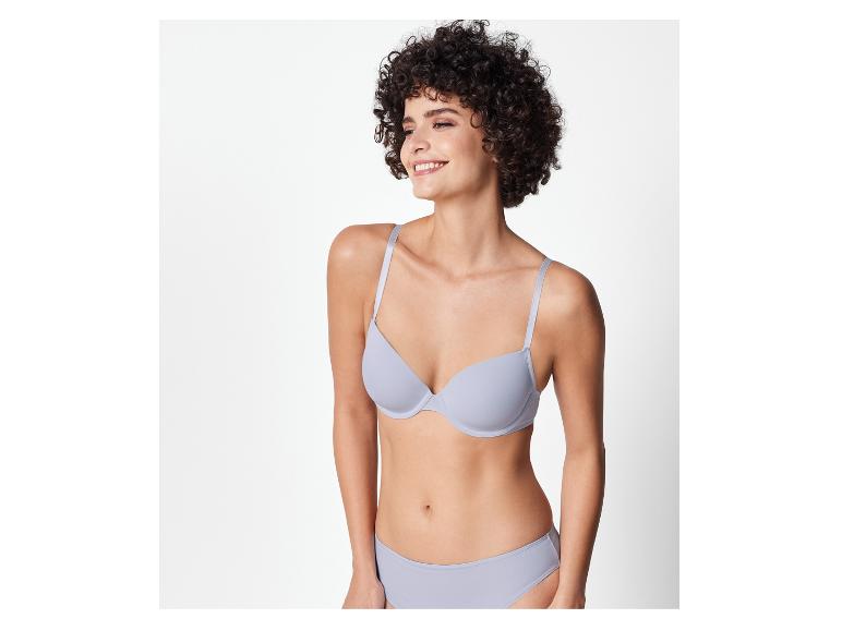 Een vrouw draagt een lichtgrijze bh en slip.