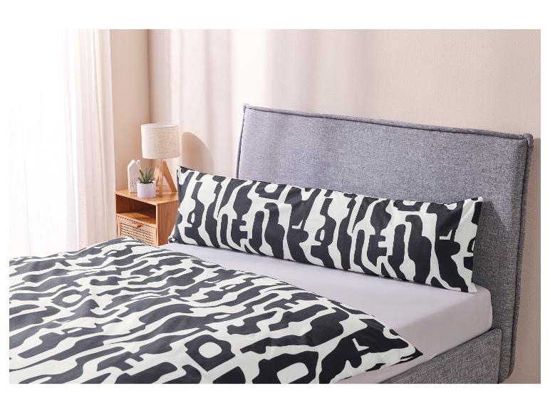 Een bed met een zwart-wit gestreept dekbedovertrek en een kussen.