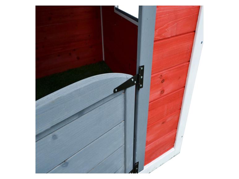 Interieur van een rood houten speelhuisje met een grijze deur en groene vloer.