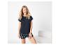 Vrouw in donkerblauw T-shirt en short met schelpenprint, lachend.