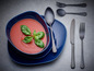 Tomatensoep in een blauwe kom met zwarte bestek