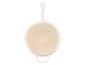 Lichtbeige ronde pan met wit handvat, van onderaf gezien.