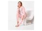 Vrouw in roze hoodie en bijpassende broek zit op een witte stoel.