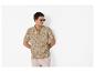 Man in een poloshirt met bladpatroon en lichte korte broek, met zonnebril