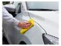 Persoon die een witte auto schoonmaakt met een gele microvezeldoek.