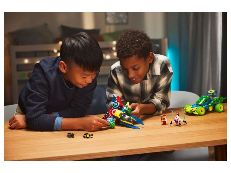 Twee jongens spelen met LEGO sets, waaronder een ruimteschip en een auto.