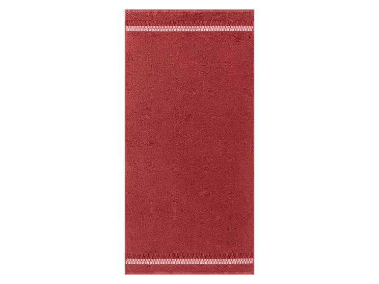 Een rode badhanddoek met een roze rand.