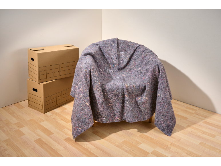 Een stoel bedekt met een beschermende hoes, naast kartonnen dozen.