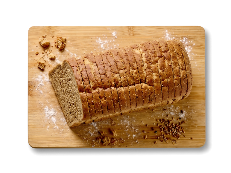 Gesneden volkorenbrood op een houten snijplank met bloem en granen