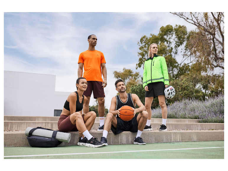 Vier personen in Crivit sportkleding poseren op een basketbalveld.