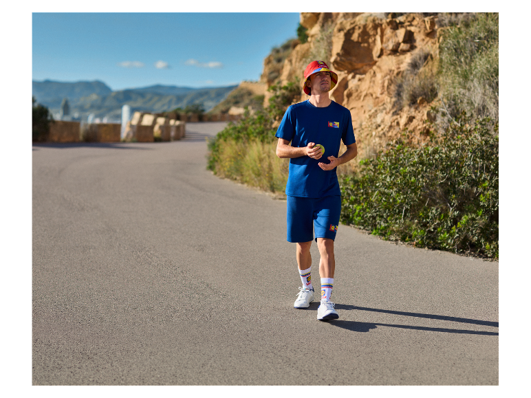 Man in Red Bull sportkleding: t-shirt, shorts en sokken.