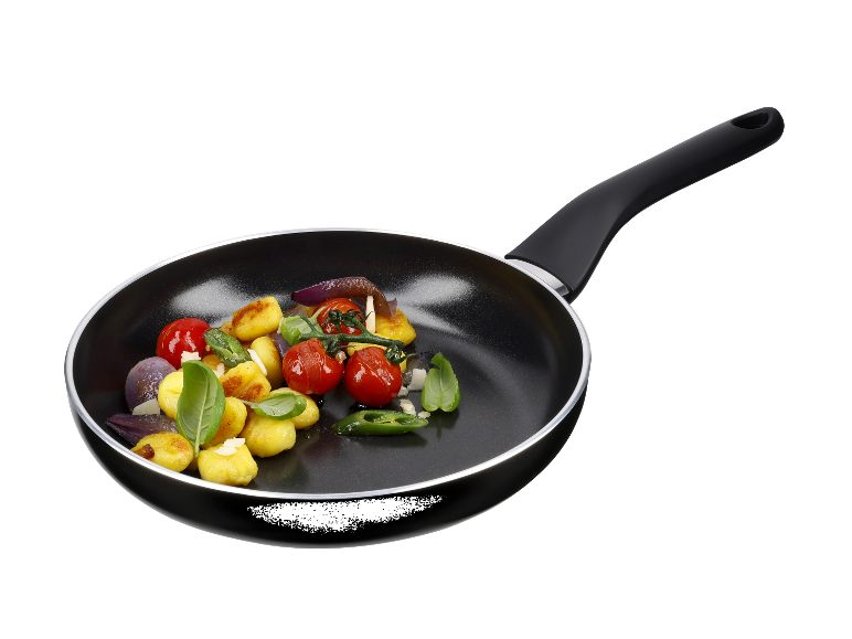 Een zwarte koekenpan met gnocchi, tomaten en uien.