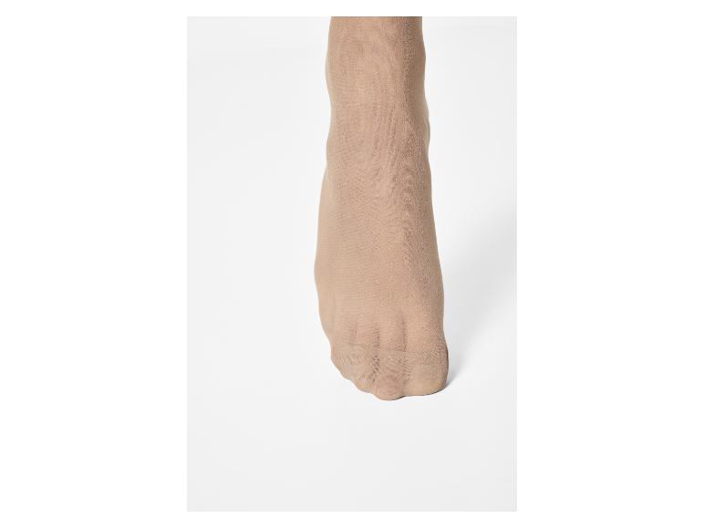 Vrouwenvoet met huidkleurige panty op een witte achtergrond.