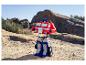 Een Optimus Prime-speelgoed staat op rotsachtig, zanderig terrein onder een heldere hemel.