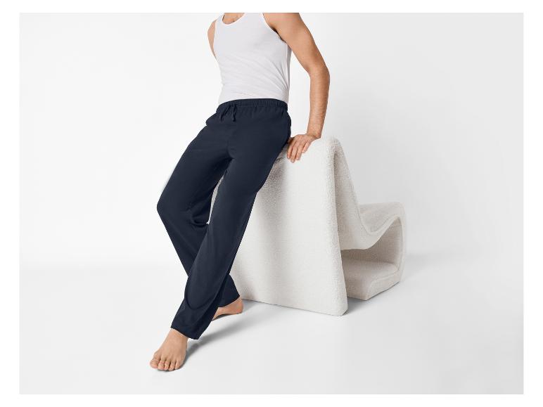 Man in wit hemd en donkerblauwe pyjamabroek, zittend op een fauteuil