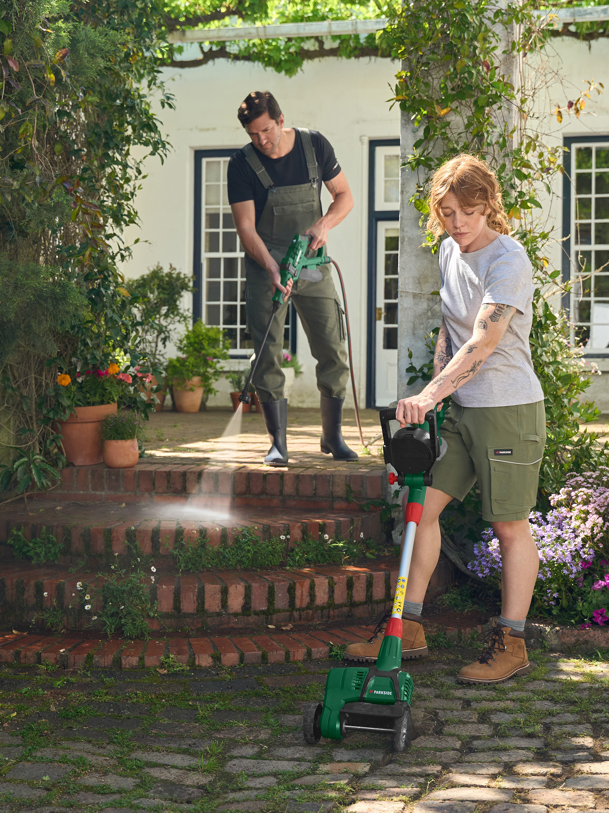 Man gebruikt hogedrukreiniger, vrouw Parkside grasmaaier in de tuin.