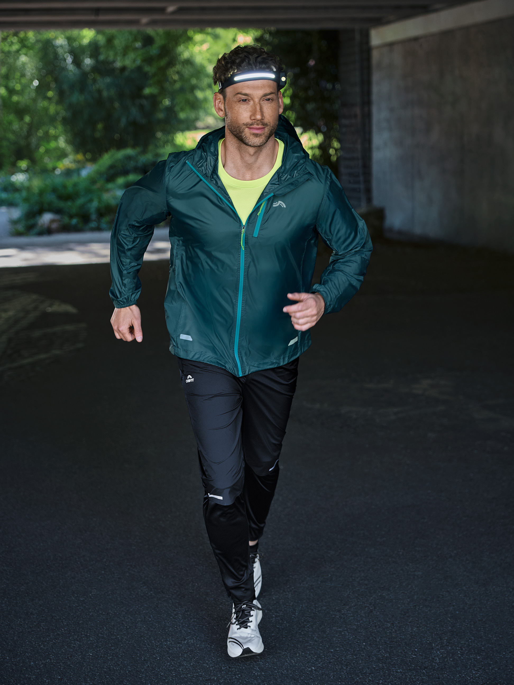 Man rent in sportkleding en hoofdlamp door een tunnel