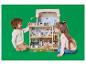 Twee kinderen spelen met een groot, meerverdiepingen poppenhuis.
