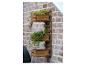 Houten verticale wandtuin met bloemen en groen aan een bakstenen muur.