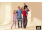Lachende familie in geruite pyjama's, vader en dochter kijken naar moeder die een lachende baby vasthoudt.