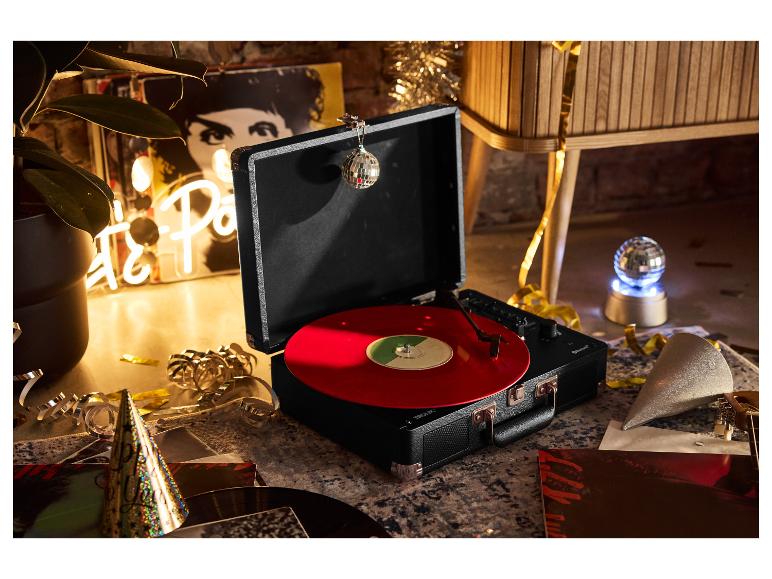 Platenspeler met rode vinylplaat, feestelijk versierd met confetti en hoedjes.