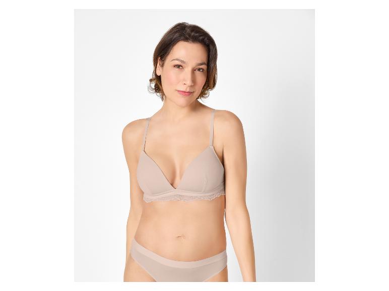 Vrouw in een beige beha en slip, recht vooruit kijkend.