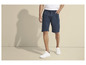 Man draagt blauwe shorts met trekkoord en witte sneakers.