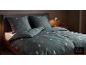 Donkergroen beddengoed met kerstmotieven, inclusief kussens en dekbed op een bed.