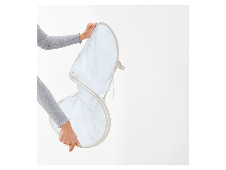 Een persoon houdt een opvouwbare wasmand van gaas vast.